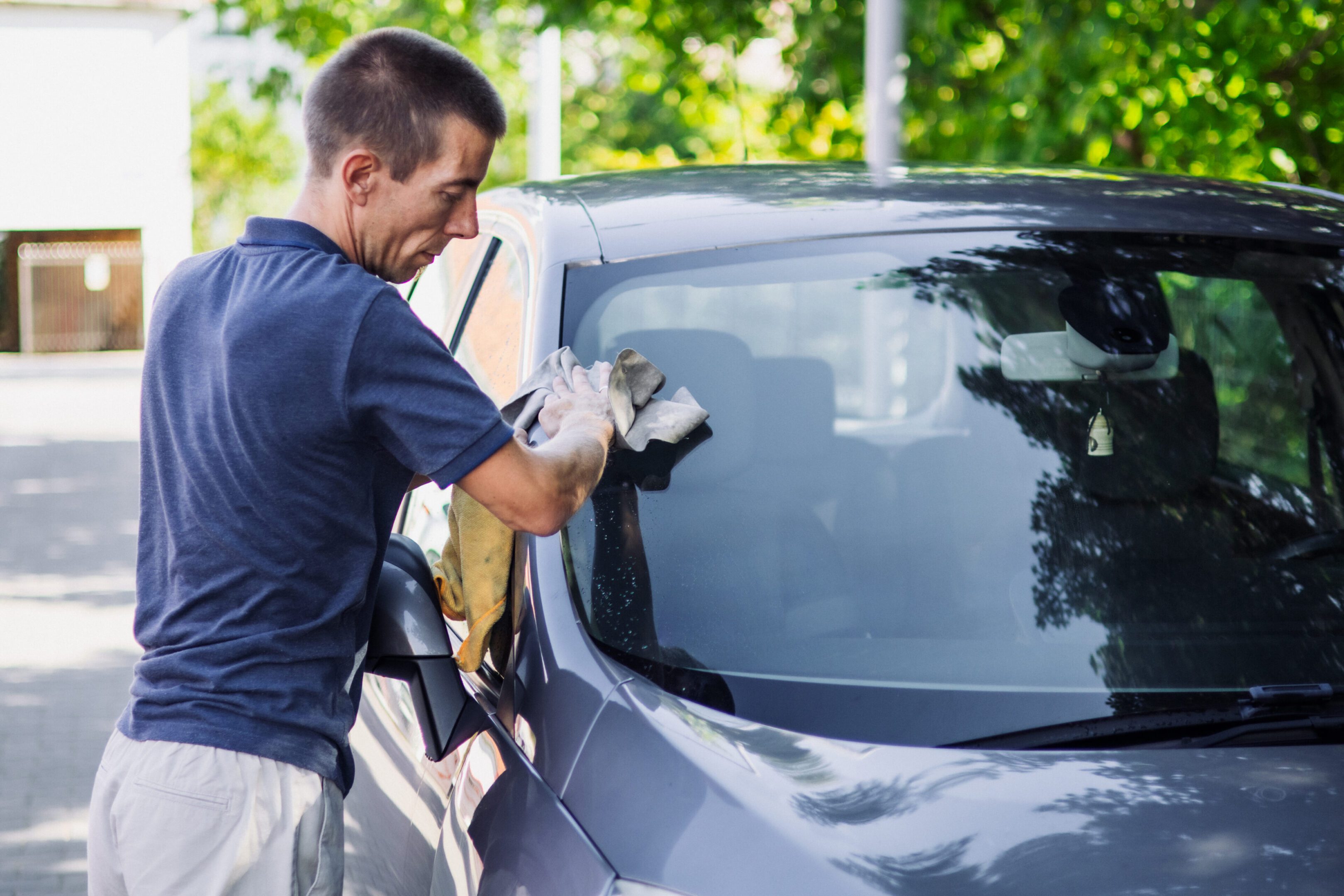 Person wiping car window outdoors